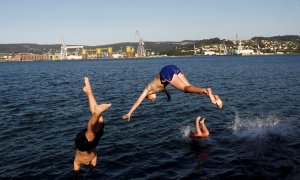 Unos jóvenes saltan al agua al atardecer en la playa del barrio de Carranza en Ferrol, Coruña, este miércoles. La Galicia de la fase 2 de desescalada disfruta del buen tiempo y de la proximidad de las playas donde disfrutan de unas temperaturas pertenecie