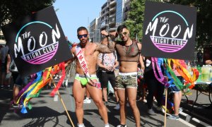 Dos participants de la desfilada del Pride BCN 2018 mostrant el cartell del club The Moon Night Club i amb roba de la marca Addicted. Júlia Pérez | ACN