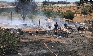 Miembros de los servicios de bomberos extinguen las llamas tras un incendio declarado en un asentamiento chabolista de Lepe, Huelva. - EFE