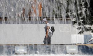 Una mujer pasa ante una fuente en Córdoba que este fin de semana registra altas temperaturas con aviso naranja decretado por la Agencia Estatal de Meteorología (Aemet). EFE/Salas