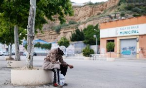 Un temporero senegalés se sienta frente a un gimnasio que alberga trabajadores estacionales de la recogida de la fruta en la localidad oscense de Fraga (Huesca).- Pau BARRENA / AFP