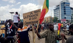 Opositores celebran las noticias sobre un supuesto golpe militar en la plaza de la Independencia de Bamako. El cartel dice:: Fin de Francia y su gobernante." REUTERS/Rey Byhre