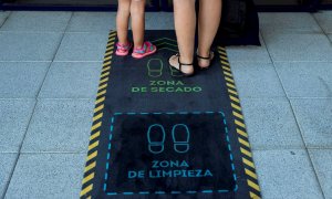 Una madre y su hija se limpian los zapatos durante la reapertura de una escuela infantil en Madrid. EFE/ Rodrigo Jiménez/Archivo