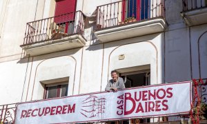 Eulàlia Castelló, portavoz de la Casa Buenos Aires, junto a la pancarta que luce en la fachada el edificio del barrio de Vallvidrera en Barcelona.