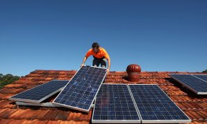 Un operario trabaja colocando paneles solares en un tejado de una vivienda.
