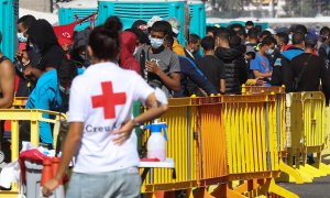 Una voluntaria de Cruz Roja junto a varios inmigrantes este jueves en el muelle de Arguineguín.