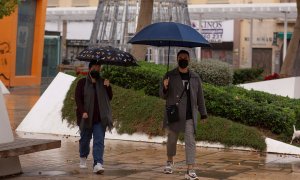 Dos personas se protegen de las lluvia bajo sus paraguas en Málaga.