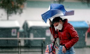 Una persona trata de protegerse de la intensa lluvia.