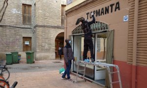 Una graffitera pinta la mañana de este lunes el rótulo de la tienda del top manta de Zaragoza.