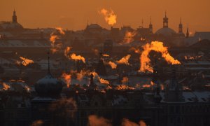 El humo sale de las chimeneas de los tejados en algunos edificios de la ciudad europea de Praga.