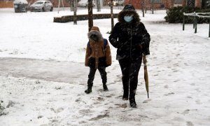 Una mujer y un niño caminan por una calle nevada en Ciudad Real.