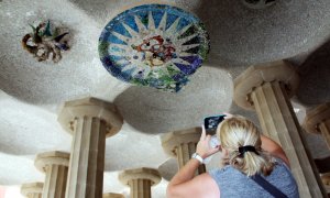 Una turista fotografia els medallons restaurats de la sala Hipòstila del Parc Güell.