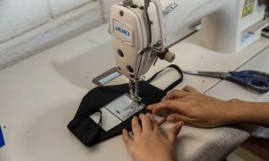 Una mujer confecciona una mascarilla transparente.