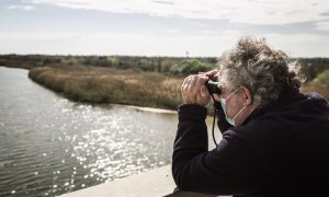 El vicepresident de DEPANA observa el Delta del Llobregat amb prismàtics per albirar els flamencs que s'hi aturen.