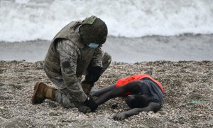 Un militar del ejército español ayuda a una persona tumbada en la orilla en una jornada marcada por las devoluciones en caliente que están efectuando a los migrantes que han entrado en Ceuta procedente de Marruecos, a 18 de mayo de 2021, en Ceuta, (España