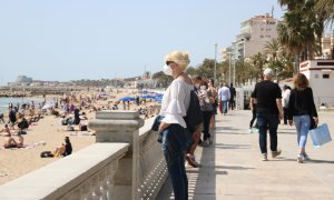 Una dona observa una de les platges de Sitges mentre passeja pel passeig. Imatge del 3 d'abril del 2021.