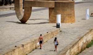 Dos personas pasean este sábado bajo un intenso Sol en el Muelle de la Sal, en Sevilla. - EFE