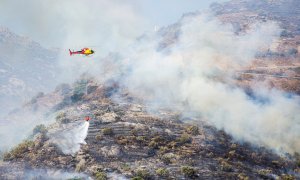 Un helicóptero realiza labores de extinción del incendio declarado en Cap de Creus, este sábado en Llançà (Girona). - EFE