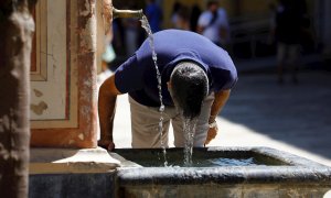 Un visitante se refresca en una fuente del Patio de los Naranjos de la Mezquita Catedral de Córdoba este sábado, en una jornada de intenso calor en la ciudad andaluza.