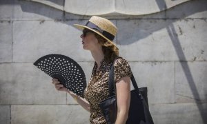 Una mujer se abanica mientras camina por la Avenida de la Constitución, en Sevilla.