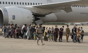 Varias personas, entre ellas niños llegan a la base aérea de Torrejón de Ardoz.