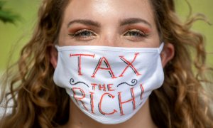 Una activista con una mascarilla en la que lleva escrito el lema  "Tax the rich" ("Impuestos para los ricos"). REUTERS/Nick Iwanyshyn