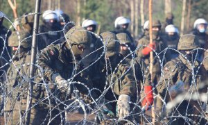 Una fotografía tomada el 9 de noviembre de 2021 muestra al personal de seguridad de Polonia detrás de una cerca de alambre de púas en la frontera entre Bielorrusia y Polonia.