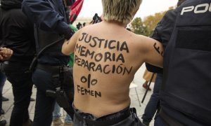 Policías nacionales sujetan a una activista de Femen que protesta frente a una concentración franquista