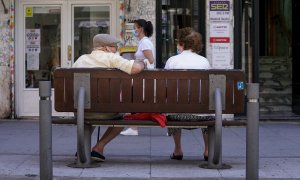 Una pareja de ancianos con mascarilla sentada en un banco, el 27 de julio de 2021, en Madrid, (España).