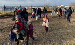Los migrantes caminan con su equipaje frente al paso fronterizo cerrado entre Bielorrusia y Polonia a 18 de noviembre de 2021.