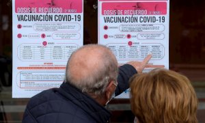 Dos personas observan un cartel con las pautas para recibir la tercera dosis de Pfizer en Valladolid este miércoles en el que el Ministerio de Sanidad ha recomendado limitar el número de participantes en los "eventos públicos y sociales", especialmente