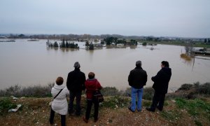 Varias personas observan los edificios de una granja sumergidos después de fuertes lluvias e inundaciones en Zaragoza. REUTERS / Vincent West