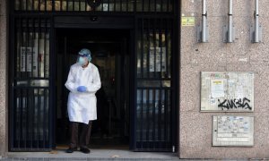 20/11/2020- Una trabajadora sanitaria sale de un portal de Madrid vistiendo un EPI (ARCHIVO)