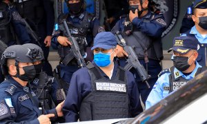 El expresidente de Honduras Juan Orlando Hernández, en el centro de la imagen, con mascarilla azul, en el momento de ser detenido el 15 de febrero de 2022 en Tegucigalpa.