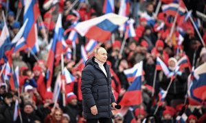 La multitud ondea banderas rusas mientras el presidente ruso Vladimir Putin camina para pronunciar un discurso durante un concierto celebrado para conmemorar el octavo aniversario de la anexión de Crimea por parte de Rusia en el estadio Luzhniki.