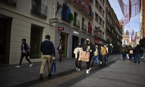 Varias personas con bolsas pasean en una calle comercial del centro de Madrid, a 2 de enero de 2022, en Madrid.