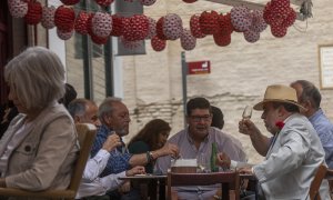 Un grupo de personas almuerzan en un bar decorado con los farolillos tradicionales de la Feria de Abril, en Sevilla, a 20 de abril de 2021.