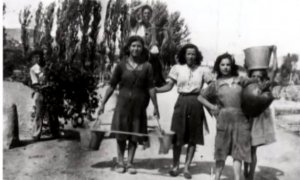 Las mujeres de Lanaja cogen agua de los barreños para hacerlo llegar a casa