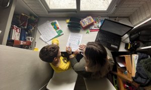 Un niño estudia y hace los deberes en casa con la ayuda de su madre.