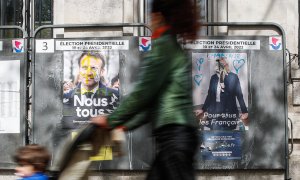 Una mujer camina junto a vallas publicitarias con carteles de los candidatos presidenciales franceses Macron y Le Pen, en París, Francia, el 18 de abril de 2022. Macron se enfrentará a la candidata del partido francés de extrema derecha Rassemblement Nati
