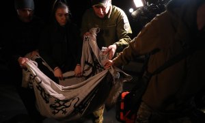 28/04/2022-Varias personas cargan con el cuerpo sin vida de un perro en el lugar de un ataque con misiles al centro de Kiev (Ucrania), este jueves 28 de abril.