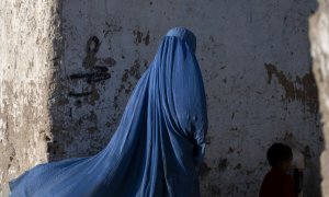 Una mujer afgana vestida con burka camina con un niño en Kabul el 28 de abril de 2022.