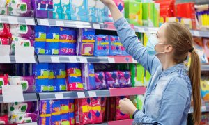 Una mujer escoge un paquete de compresas en un supermercado.