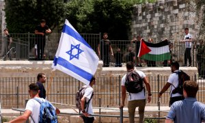 Los israelíes se paran con una bandera israelí frente a los palestinos con la bandera palestina junto a la puerta de Damasco a la Ciudad Vieja de Jerusalén el 29 de mayo de 2022.