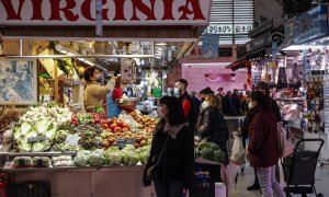Varias personas compran en un puesto de fruta y verdura en el Mercado Central de Valencia, a 24 de marzo de 2022, en Valencia, Comunidad Valenciana, (España).