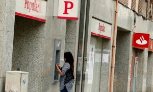 Una foto de junio de 2017 de una mujer utilizando el cajero automático de una oficina del extinto Banco Popular, junto a otra sucursal del Banco Santander. REUTERS/Albert Gea