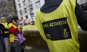 Varias personas portan una banderola amarilla gigante de Amnistía Internacional que reza 'Que ni los besos te callen' en una manifestación contra la ley mordaza, a 13 de febrero de 2022, en Madrid.