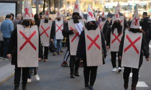 Varios manifestantes vestidos con petos tachados con cruces y capirotes blancos con niños dibujados, durante la manifestación en defensa de los menores tutelados, en el centro de Madrid el 29 de enero de 2022.