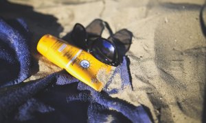 06/08/2022. Un bote de crema solar sobre la arena de playa, a 15 de diciembre de 2017.