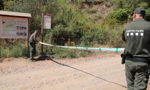 Dos Agents Rurals col·loquen una cinta per impedir l'accés al Parc Natural de la Serra de Montsant des de la Cartoixa d'Escaladei.